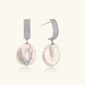 Rhodium-plated silver curved stud with pave stones and baroque pearl drop on white background