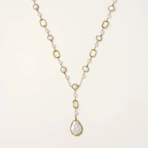 Y-shaped gold necklace with alternating geometric links, freshwater pearls, and baroque pearl pendant on cream background