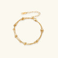 Three-strand gold-plated bracelet with clustered ball beads and adjustable clasp on cream background