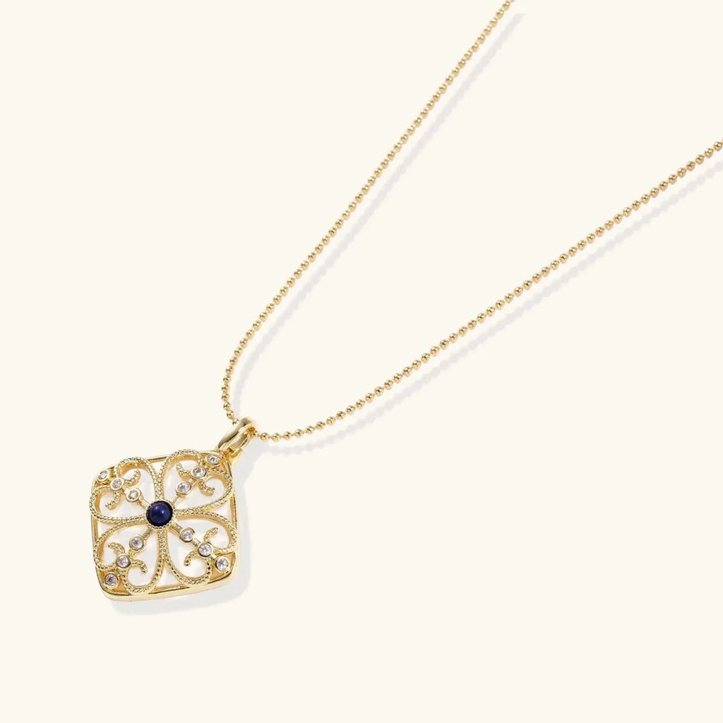 Gold filigree pendant with quatrefoil design, deep blue lapis lazuli center, clear crystal accents on ball chain